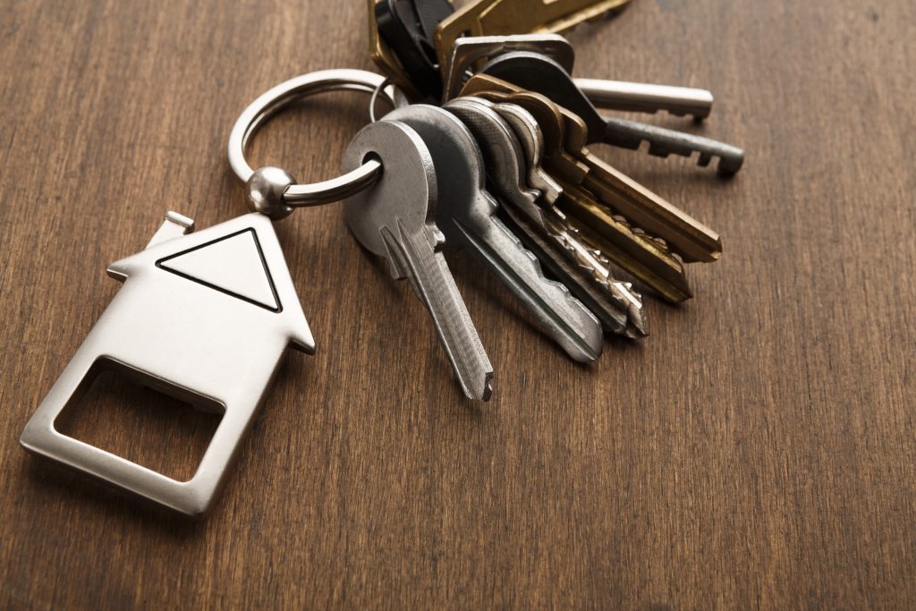 Bunch of keys with house shaped keychain on white wood