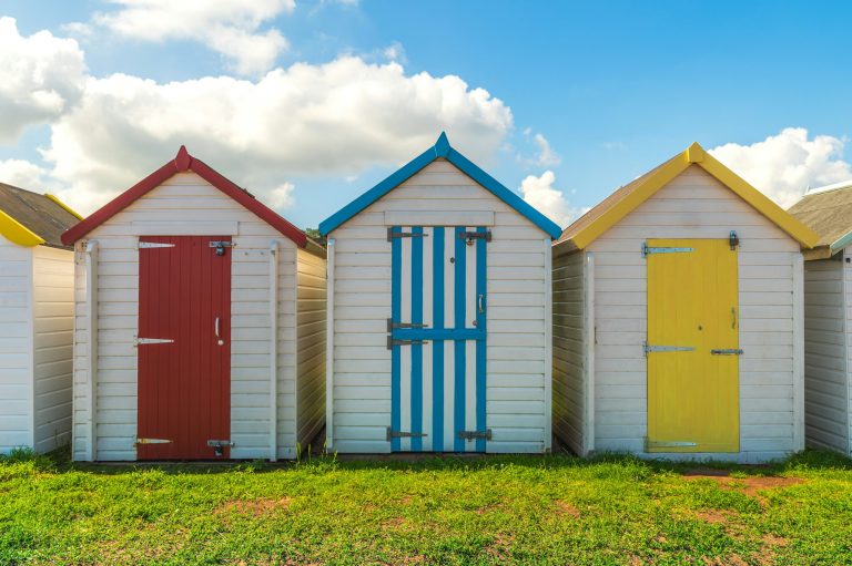 Colorful small beach houses. Multicolored beach sheds. Variety of painted beach shacks. Beach huts.